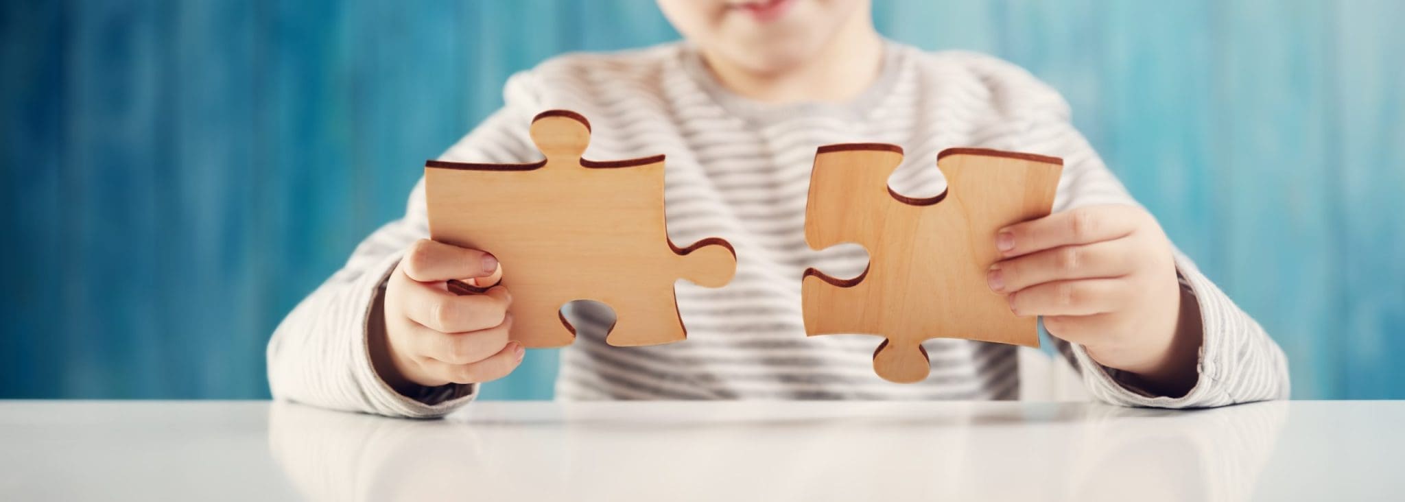 Little child holding puzzle pieces and trying to solve it